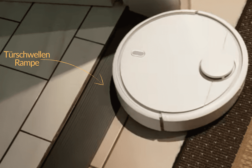 Ein Staubsauger Roboter fährt über eine Türschwellenrampe für Saugroboter in das nächste Zimmer.